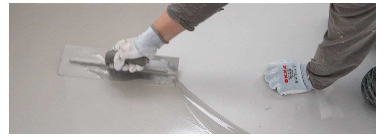 Person, die Reparaturen an Gussböden mit einer Flachkelle durchführt